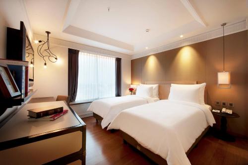 a hotel room with two beds and a television at De Paviljoen Bandung in Bandung