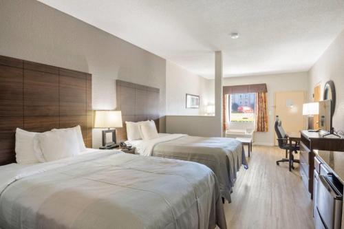 a hotel room with two beds and a desk at Quality Suites Hickory South in Hickory