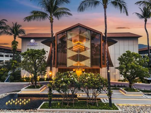 a building with a glass facade with palm trees at DoubleTree by Hilton Phuket Banthai Resort in Patong Beach