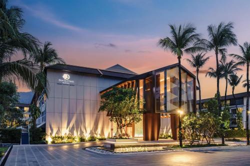 a building with palm trees in front of it at DoubleTree by Hilton Phuket Banthai Resort in Patong Beach