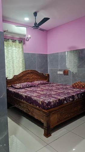 ein Schlafzimmer mit einem Holzbett und lila Wänden in der Unterkunft SVS Grands in Ālamūru