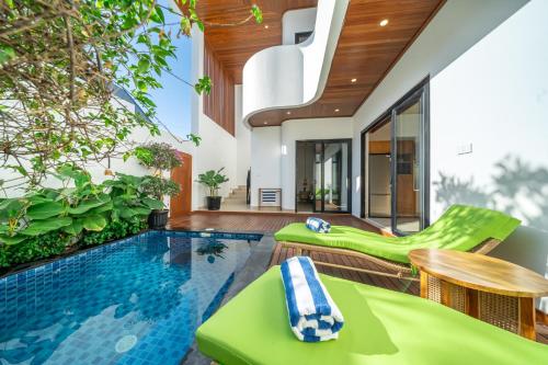 an indoor pool with green chairs and a swimming pool at Cassandra Villas - Tropical Private Pool Escape near Beach in Sanur