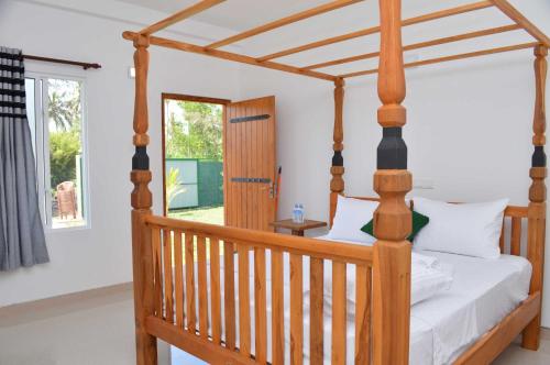 a bedroom with a wooden canopy bed with white pillows at Airport Green Hotel in Katunayake