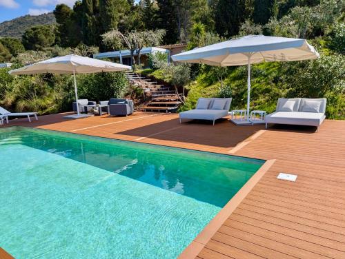 a swimming pool with two umbrellas and two chairs and a deck at Villa Torre Conca Cefalu Coast in Finale