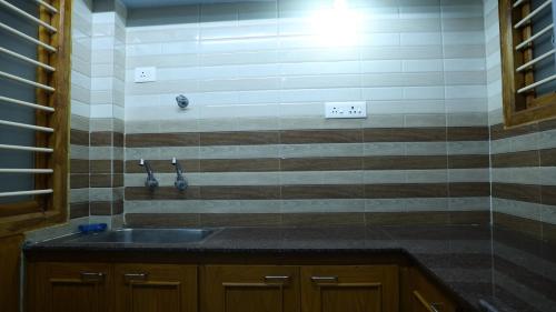 a kitchen with a sink and a tiled wall at Moon Hug Boutique Beach House in Auroville