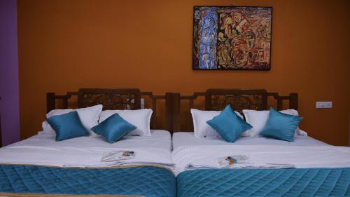 two beds in a room with blue and white pillows at Moon Hug Boutique Beach House in Auroville