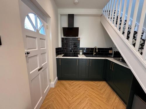 a kitchen with green cabinets and a staircase at Peaceful Self-Contained Apartment in Beckenham