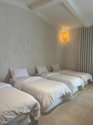a room with three beds with white sheets at Athens Resort in Madīnat an Nahḑah