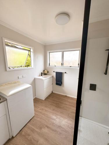 a laundry room with a sink and a washing machine at The Bach at One Tree Point in One Tree Point
