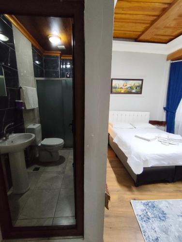 ein Schlafzimmer mit Bett und ein Badezimmer mit Waschbecken in der Unterkunft Kule Pansiyon in Bursa