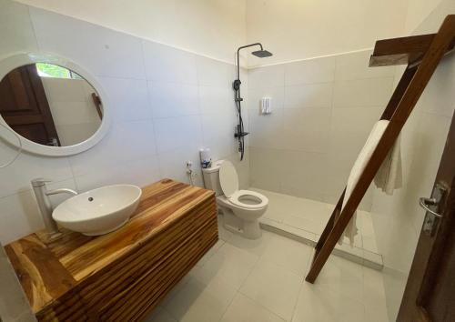 a bathroom with a sink and a toilet and a mirror at Minah bungalows in Nungwi