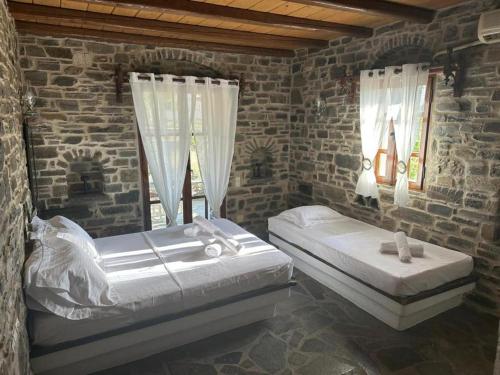 a bedroom with two beds in a brick wall at Paros Casa Prive in Vrachonisída Loúmpinas