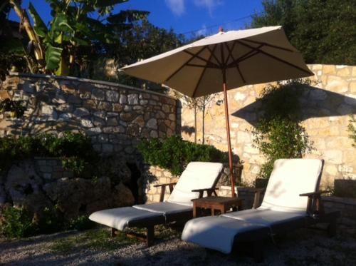 two lounge chairs and an umbrella and an umbrella at Harry's Studios 1 in Gaios