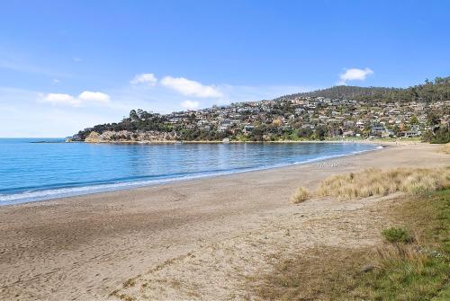 a sandy beach with houses on a hill next to the water at Mirramar House in Kingston Beach
