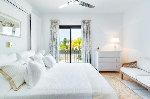 a white bedroom with a large bed and a window at 4 Bedroom Villa With Private Pool in Maroni