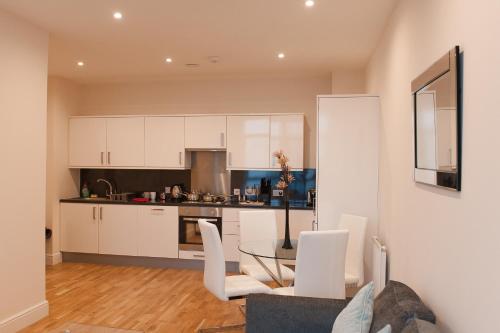 a kitchen with white cabinets and a table and chairs at PSF Panorama Apartments in Ashford