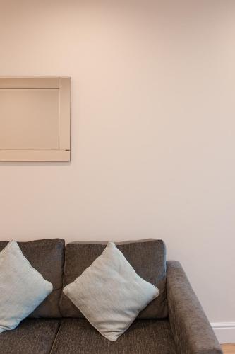 a couch against a white wall with pillows on it at PSF Panorama Apartments in Ashford