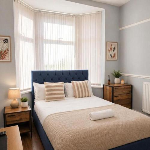 a bedroom with a large bed with a blue headboard at The Range Nestled Nook in Manchester