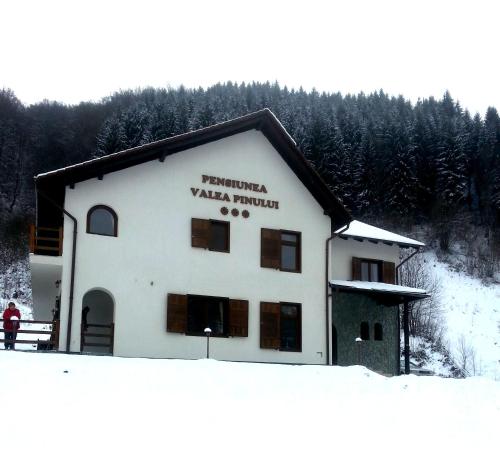 a building with a sign on it in the snow at Pensiunea Valea Pinului in Rau Sadului