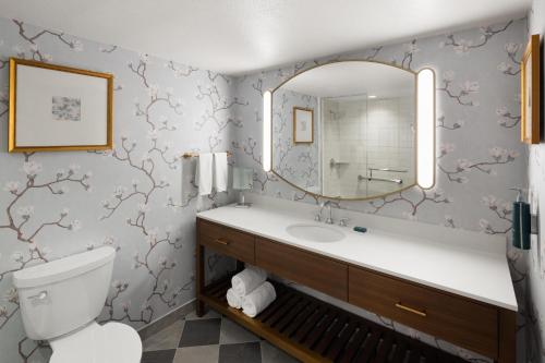 a bathroom with a toilet and a sink and a mirror at Hilton New Orleans Riverside in New Orleans