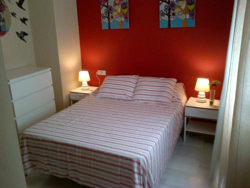 1 dormitorio con 1 cama con pared roja en Triana Pureza, en Sevilla