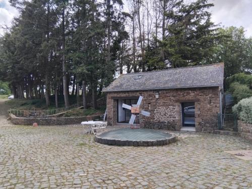 a small brick building with a patio in a yard at Maisonnette meublée à la campagne in Ernée