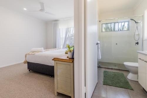 a bedroom with a bed and a shower and a toilet at 10 Beach Houses in Agnes Water