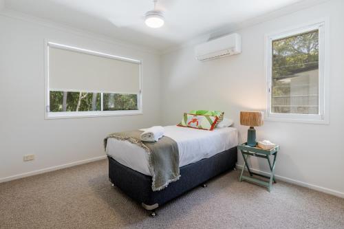 a bedroom with a bed and two windows at 10 Beach Houses in Agnes Water