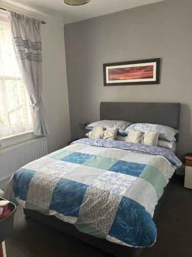 ein Schlafzimmer mit einem Bett mit einer blau-weißen Steppdecke in der Unterkunft The keyberry in Newton Abbot