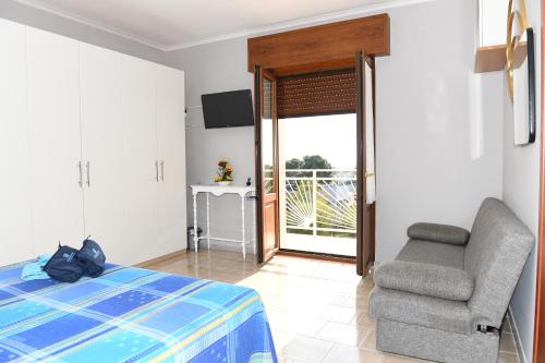 a bedroom with a bed and a chair and a balcony at B&B Il Canto Del Mare in Pulsano