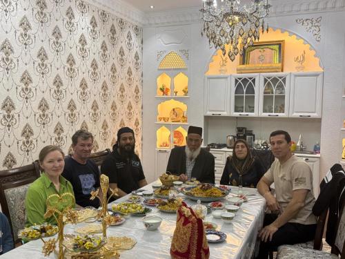 a group of people sitting around a table with food at Ashur Bobo in Samarkand
