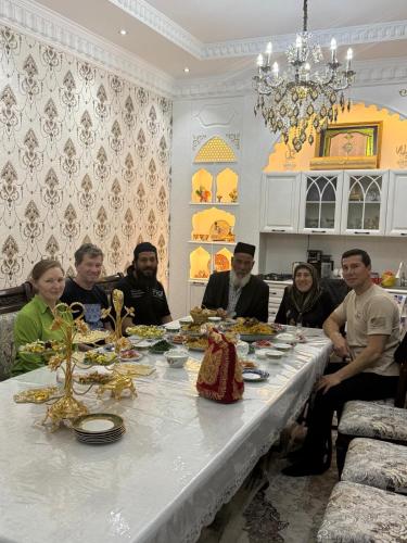 a group of people sitting around a table with food at Ashur Bobo in Samarkand