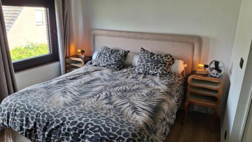 a bed with a black and white comforter and a window at Apartment in Vichte 1 Bedroom in Anzegem