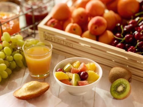 a table with a bowl of fruit and a glass of orange juice at ibis Blois Centre Château in Blois
