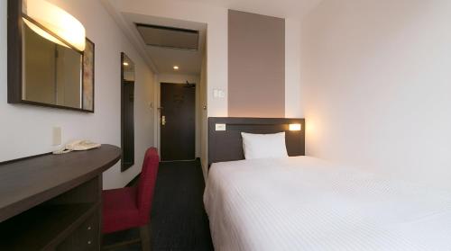 a bedroom with a white bed and a red chair at Urban Hotel Kyoto in Kyoto