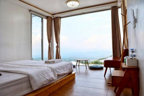 a bedroom with a bed and a large window at ดอกฟ้า ม่อนแจ่ม in Mon Jam
