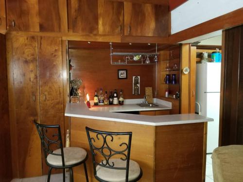 a kitchen with a bar with two chairs and a refrigerator at Charming 3-Bedroom House Steps from Luquillo Beach in Luquillo