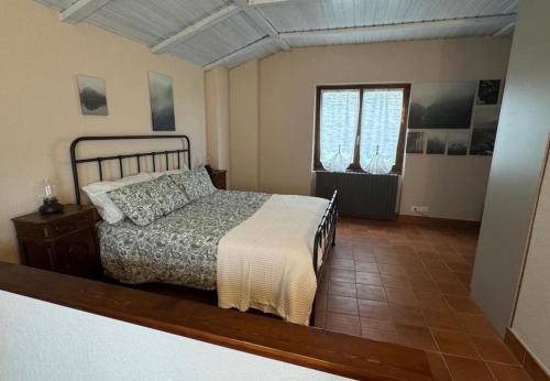 a bedroom with a bed and a window at L'Angulin in Vezzo