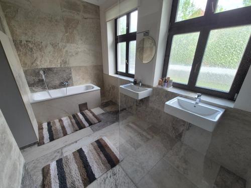 a bathroom with two sinks and a tub and mirrors at The Gusto apartmán in Chomutov