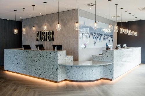 a lobby with a reception desk with pendant lights at Motel One Hamburg-Alster in Hamburg