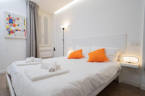 a white bed with orange and white pillows on it at Seven Thousand Apartment in Brescia