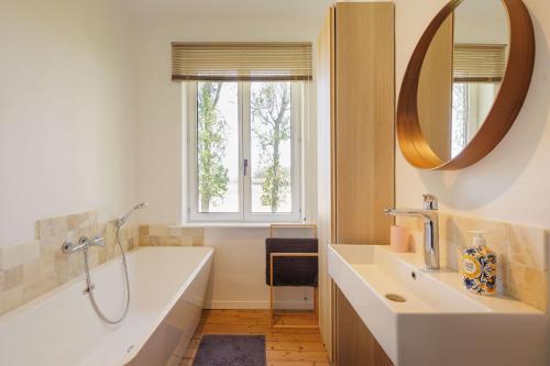a bathroom with a tub and a sink and a mirror at Huisje aan de Schelde in Spiere