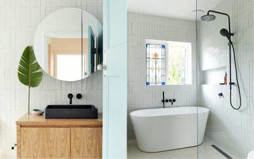 a bathroom with a tub and a sink and a mirror at Bruns Surf Shack in Brunswick Heads