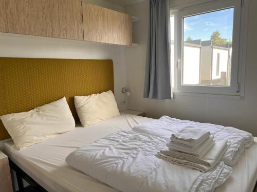 a bed with white sheets and pillows and a window at Camping Resort Riegersburg in Riegersburg