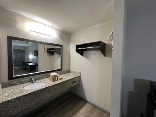 a bathroom with a sink and a large mirror at Speedway Inn & Suites in Griffin