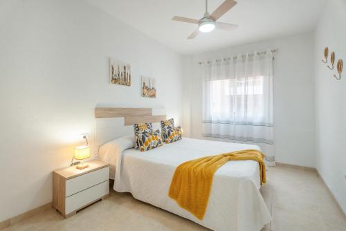 a white bedroom with a bed and a ceiling fan at Brisa Caletillas in Punta Larga