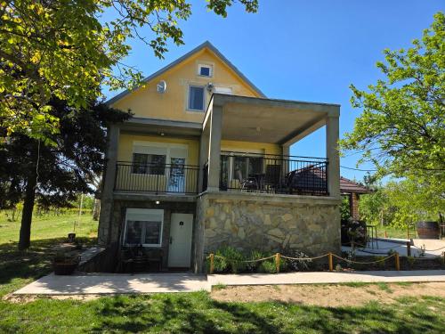 a large yellow house with a porch and balcony at Casa Horizont in Slankamenački Vinogradi