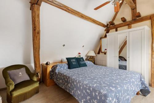a bedroom with a bed and a chair at Gîte Roses De Loire in Bréhémont
