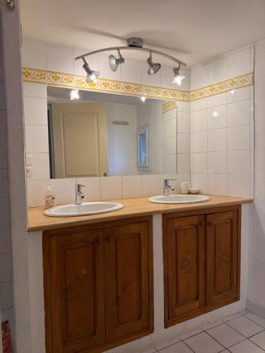 a bathroom with two sinks and a large mirror at Ma maisonnette en Cévennes in Le Vigan