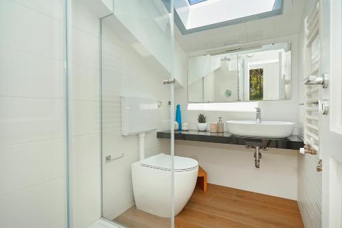 a white bathroom with a toilet and a sink at Villa Gabbiano - Scopello-Villas in Scopello